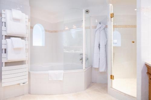 a white bathroom with a shower and a sink at Grand Hôtel Courchevel 1850 in Courchevel