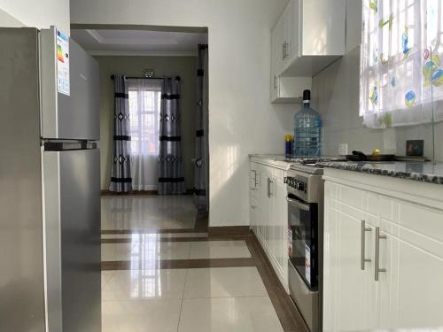 a kitchen with white cabinets and a stainless steel refrigerator at Mtei Safaris Hostel in Arusha