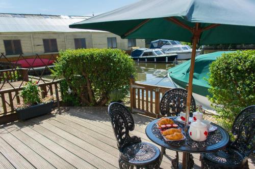 a table with a plate of food and an umbrella at Quayside Cottage - Norfolk Holiday Properties in Wroxham
