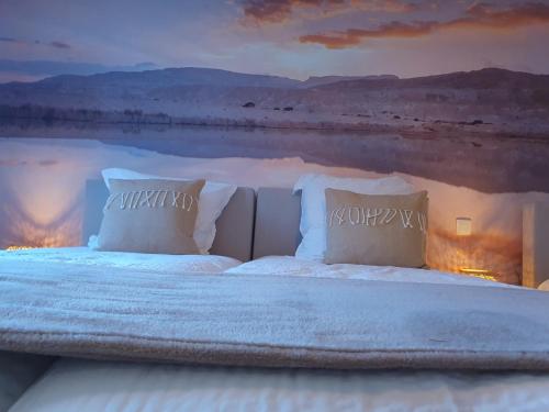a bed with white sheets and pillows in the middle of a desert at Vakantiewoning De Gavers in Geraardsbergen
