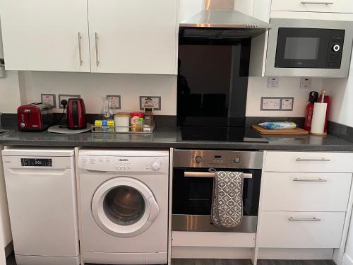 a kitchen with a washing machine and a microwave at Premier Apartment C in Broxburn