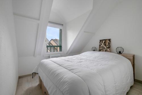 ein weißes Schlafzimmer mit einem Bett und einem Fenster in der Unterkunft Maison familiale à 500m de la plage in Piriac-sur-Mer