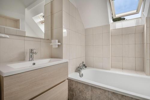 ein weißes Badezimmer mit einer Badewanne und einem Waschbecken in der Unterkunft Maison familiale à 500m de la plage in Piriac-sur-Mer