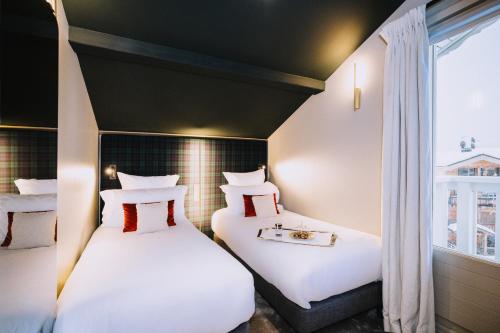 two beds in a room with a window at Hotel Le Chabichou in Courchevel