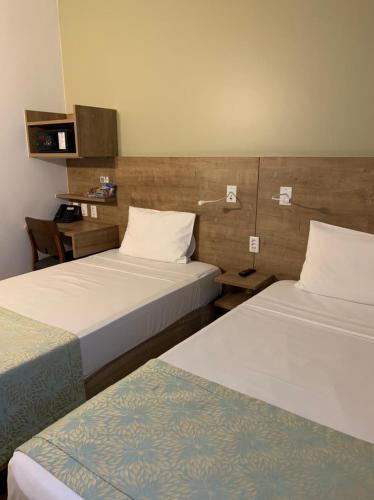 a hotel room with two beds and a desk at Sleep Inn Praia do Canto in Vitória