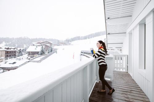 a woman standing on a balcony looking out at the snow at Hotel Le Chabichou in Courchevel