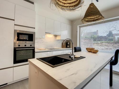 a white kitchen with a sink and a stove at Vakantiewoning De Gavers in Geraardsbergen