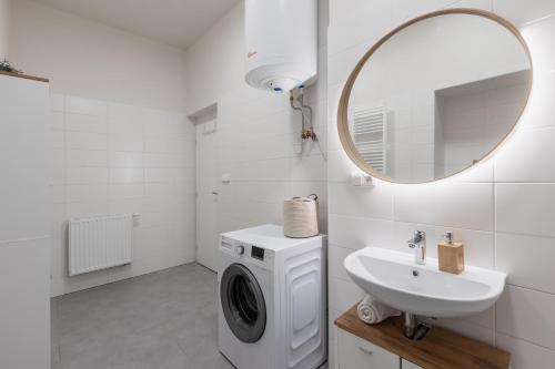 een witte badkamer met een wasmachine en een wastafel bij BOHO RÁJ v centru / /gril/ /balkón in Olomouc