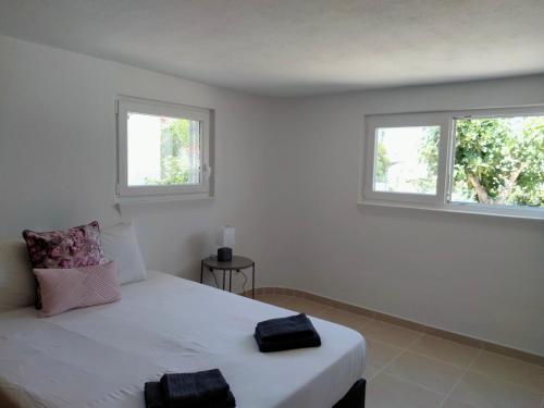 a bedroom with a white bed with two windows at Vila Horizonte in Carvoeiro