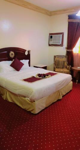 Cette chambre dispose d'un grand lit avec un tapis rouge. dans l'établissement فندق كراون نجران, à Najran