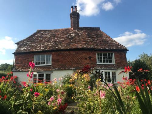 an old house with flowers in front of it at The Studio in Wisborough Green