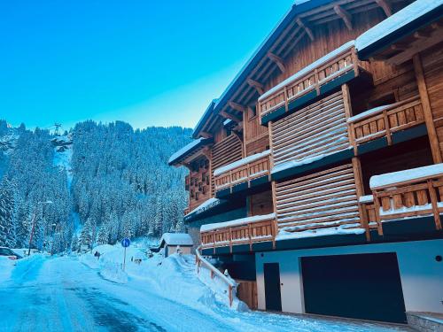 a building with snow on the ground next to a road at Hameau des Prodains - Résidence in Morzine