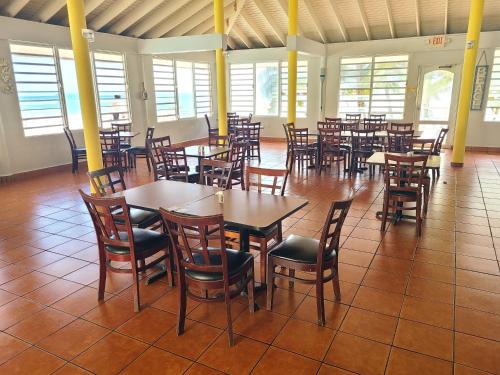 ein Esszimmer mit Tischen, Stühlen und Fenstern in der Unterkunft Parador Maunacaribe - Maunabo in Maunabo