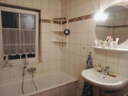 a bathroom with a tub and a sink and a mirror at Drei-Insel-Blick Neßmersiel in Neßmersiel