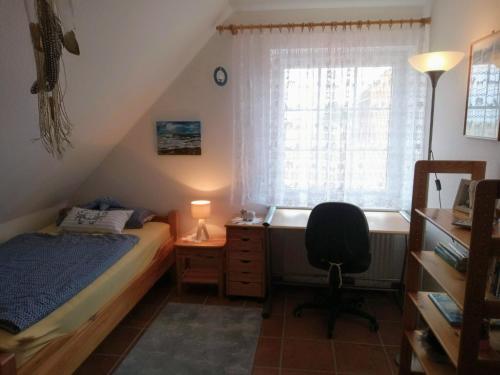 1 dormitorio con cama, escritorio y ventana en Drei-Insel-Blick Neßmersiel, en Nessmersiel