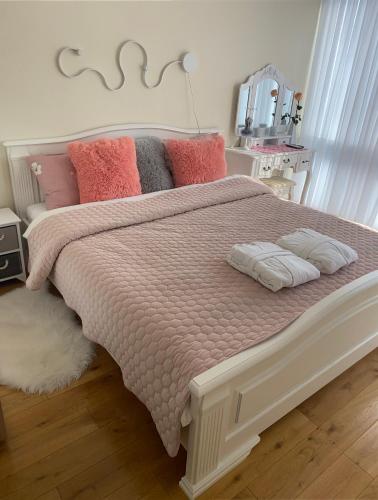 a bedroom with a large bed with pink blankets and pillows at Snieguolės apartamentai in Palanga