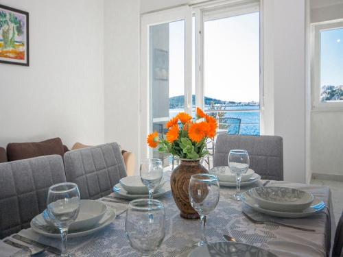 una mesa con vasos y un jarrón con flores naranjas. en Apartments Happy Holiday en Rogoznica