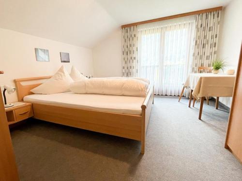 a bedroom with a bed and a table and a window at Haus Elisabeth Netzer in Sankt Gallenkirch