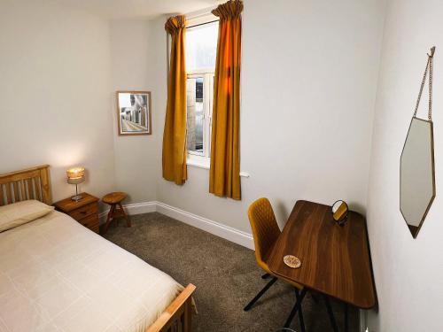 1 dormitorio con cama, escritorio y ventana en Orchard Cottage, en Ventnor