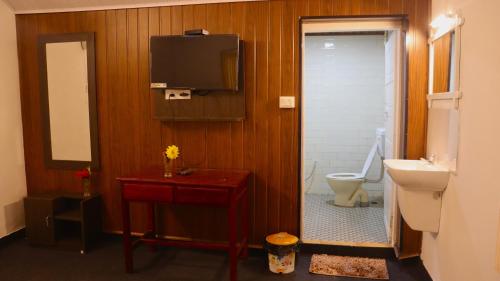 a bathroom with a toilet and a tv on the wall at GOLDEN GREEN in Munnar