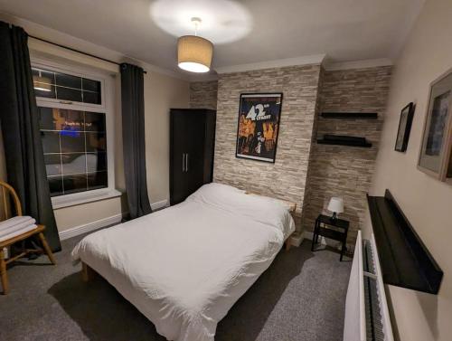 una camera con un letto bianco e un muro di mattoni di Penarth Town Terrace, close to cafes, beaches, Cardiff a Cardiff