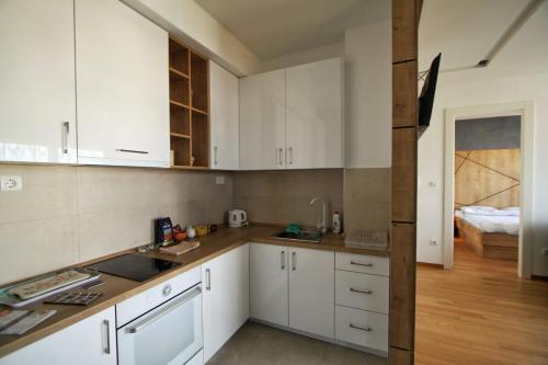 a kitchen with white cabinets and a bed in the background at Downtown apartment in Banja Luka