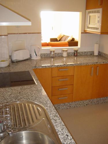 a kitchen with a sink and a couch in a window at Apartamento Pelicanos Golf & Beach - spacious and modern with terrace and private pool in Roquetas de Mar