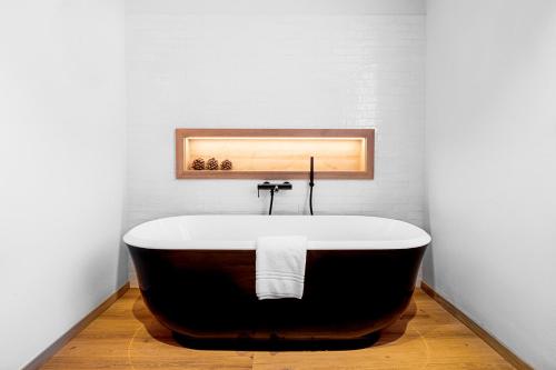 La salle de bains est pourvue d'une baignoire et d'un mur blanc. dans l'établissement ALPINE INN Davos, à Davos