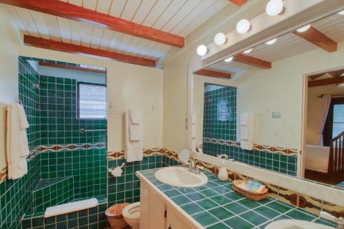 uma casa de banho com azulejos verdes, um lavatório e um espelho. em Condo #27 @ Beachside Villas em Dangriga