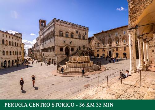 a group of people walking around a plaza with a fountain at Agriturismo Sant'Angelo holiday farm in Gualdo Cattaneo
