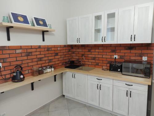 a kitchen with white cabinets and a brick wall at Dwór Bysina in Myślenice