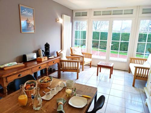 - un salon avec une table, des chaises et des fenêtres dans l'établissement La Minoterie, à Tessy-sur-Vire