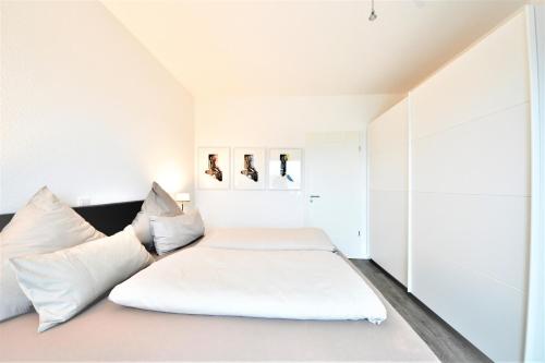 a bedroom with a white bed with pillows at Seeblick Roter Sand in Wangerooge