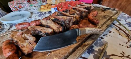 una mesa con una tabla de cortar con carne y un cuchillo en Hostal Jardín de Luque en San Lorenzo