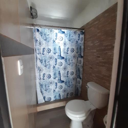 a bathroom with a toilet and a blue shower curtain at Hotel Mi Paraíso Río Dulce in Castillo de San Felipe