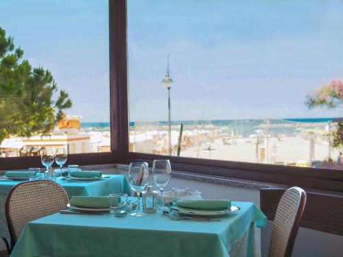 a table with blue tables and chairs with a view of the ocean at Hotel Colorado Cesenatico in Cesenatico