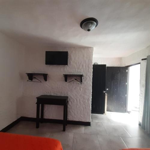 a living room with a table and a tv on a wall at Hotel Mi Paraíso Río Dulce in Castillo de San Felipe