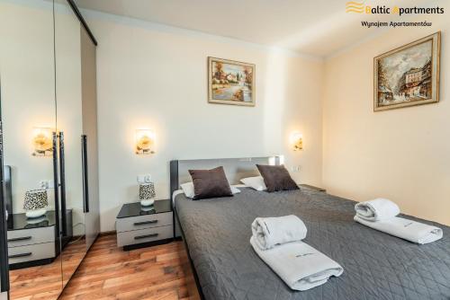 a bedroom with a large bed with two towels on it at Baltic Apartments - Villa Mistral in Świnoujście