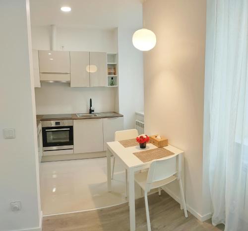 a white kitchen with a white table and chairs at Balance appartment - Le Locle in Le Locle