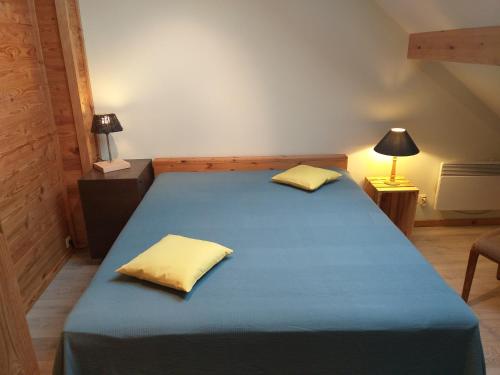 een slaapkamer met een blauw bed met 2 gele kussens bij Gîte l'Ecole de ma Mère in Bertogne