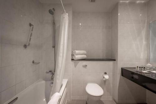 a bathroom with a tub and a toilet and a sink at Hotel Woodstock Ennis in Ennis