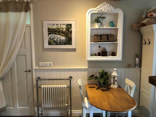 uma sala de jantar com uma mesa de madeira e um radiador em BnB onder de Blauwe Hemel em Vlijmen