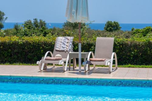twee stoelen en een parasol naast een zwembad bij Monambeles Villas in Svoronata