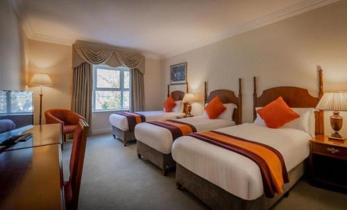 a hotel room with two beds and a couch at Hotel Woodstock Ennis in Ennis