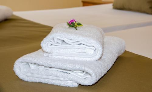 una pila de toallas en una cama con una flor en la parte superior en Dias Hotel Apartments en Agia Marina Nea Kydonias