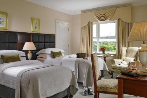 a hotel room with three beds and a window at Hotel Woodstock Ennis in Ennis