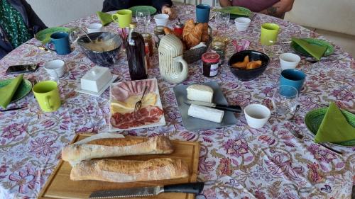 une table avec un tissu de table, du pain et d'autres aliments dans l'établissement Villa Nymphée, à Vaison-la-Romaine