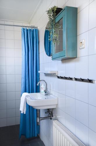 a bathroom with a sink and a blue shower curtain at in het Dal in Buren