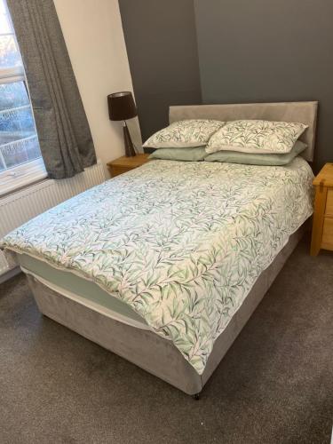 uma cama grande num quarto com uma colcha e almofadas em Flat in Leamington Spa town centre em Leamington Spa