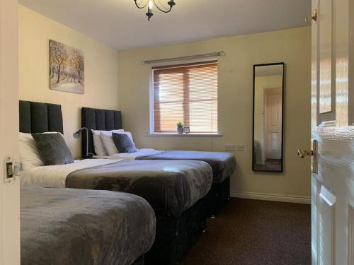 a bedroom with two beds and a window and a mirror at House - 10min to City Centre - Sleeps 4 - Parking in Birmingham